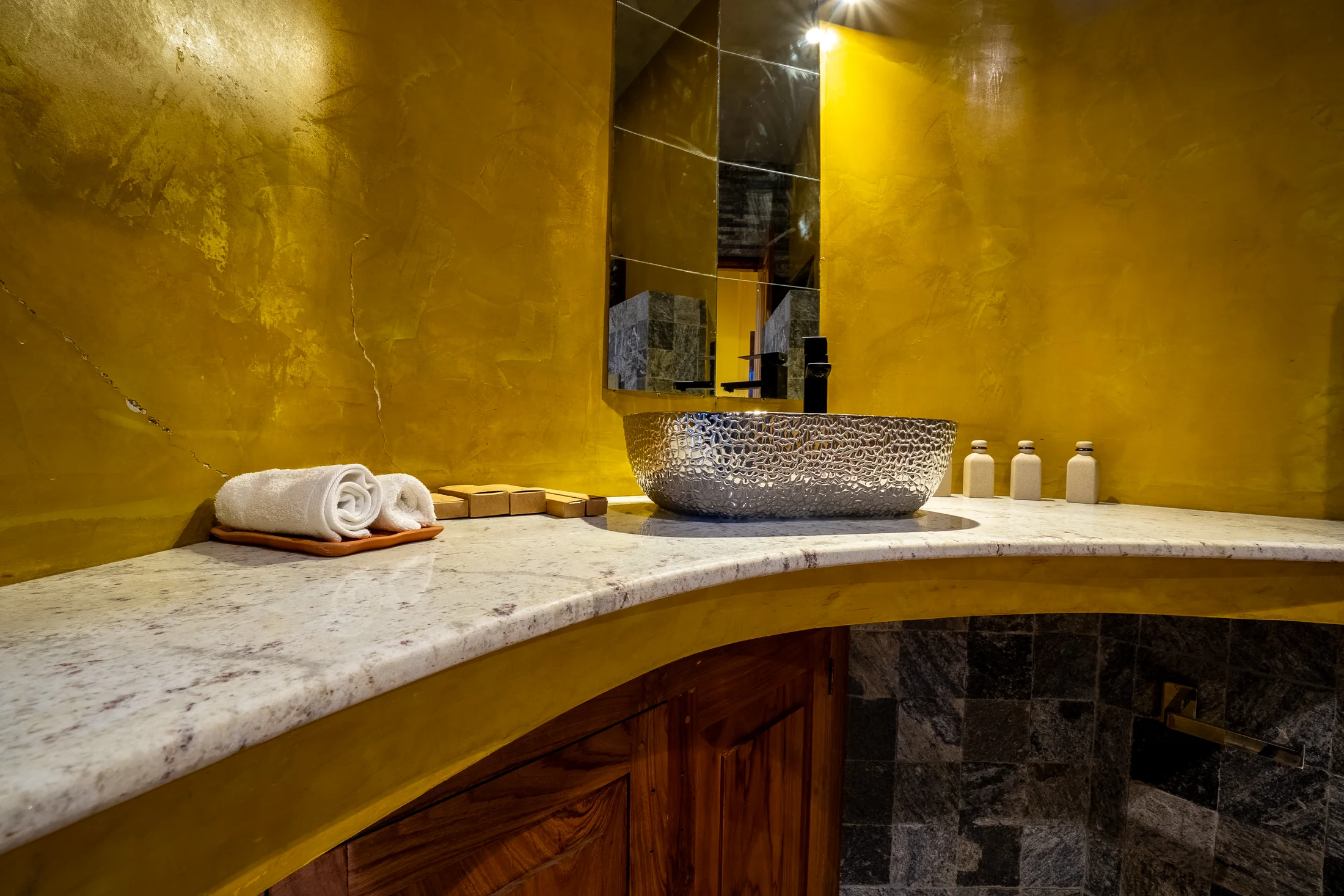 En-suite bathing area with textured stone and warm lighting