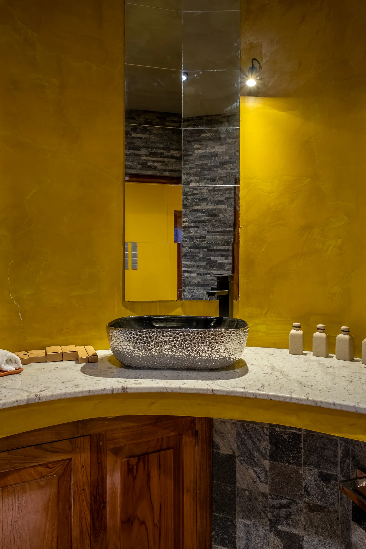 En-suite bathing area with textured stone and warm lighting